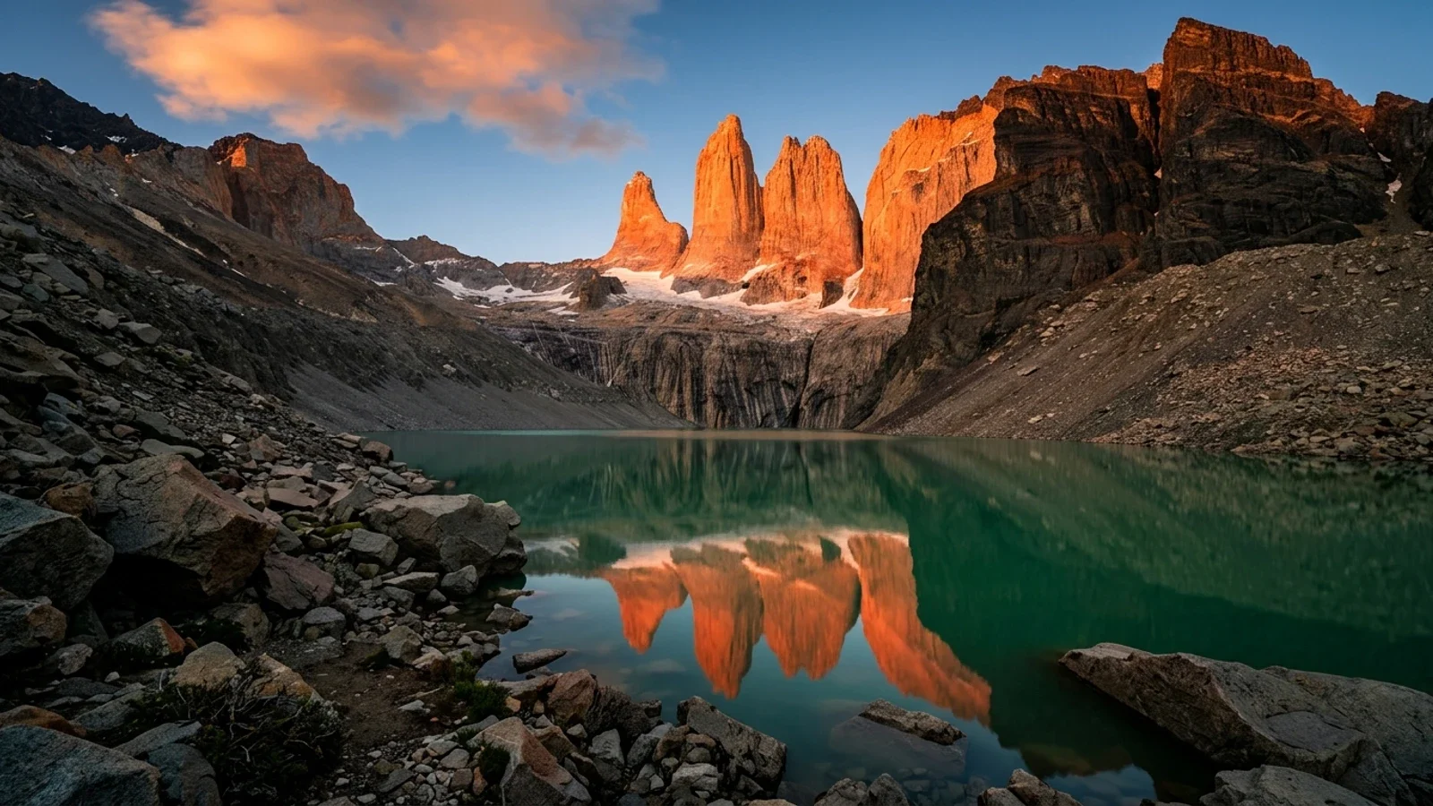 Ba đỉnh tháp đá granite sừng sững của Torres del Paine soi bóng xuống hồ ngọc lam lúc bình minh nhuộm đỏ